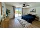 Cozy bedroom featuring a ceiling fan, wood-look floors, and sliding glass doors to a private, fenced backyard patio at 10224 Old Orchard Ln, Port Richey, FL 34668