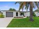 Charming single-story home with a manicured lawn, mature palm trees, and an attached two-car garage at 10224 Old Orchard Ln, Port Richey, FL 34668