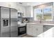 Bright kitchen features stainless steel appliances, white cabinets, designer tile backsplash, and light countertops at 10224 Old Orchard Ln, Port Richey, FL 34668