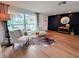 Bright living room with modern accent wall, wood floors, and large picture window showcasing the landscaped front yard at 10224 Old Orchard Ln, Port Richey, FL 34668
