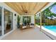 Covered patio with a wood ceiling, comfortable seating, and views of the sparkling pool, perfect for outdoor enjoyment at 10224 Old Orchard Ln, Port Richey, FL 34668