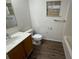 Bathroom with a single sink vanity, toilet, and tiled bathtub/shower combo with wood-look floors at 11308 Mahopac Rd, Weeki Wachee, FL 34614