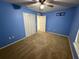 Comfortable bedroom featuring carpeted floors, a ceiling fan, closet, and blue painted walls at 11308 Mahopac Rd, Weeki Wachee, FL 34614