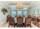 Formal dining room features an elegant chandelier, large windows, and seating for eight, perfect for entertaining at 11510 Lakeview Dr, New Port Richey, FL 34654