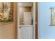 Hallway with paintings, neutral walls and view into mud room with white door at 11510 Lakeview Dr, New Port Richey, FL 34654
