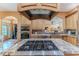 Granite island with gas cooktop, stainless appliances, custom range hood, and seamless transition to other living areas at 11510 Lakeview Dr, New Port Richey, FL 34654