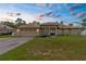 Charming single-story home featuring a well-manicured lawn and an attached two-car garage at dusk at 12026 Penguin Ave, Weeki Wachee, FL 34614