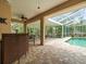 Covered lanai with brick flooring, a ceiling fan, bar seating, and comfortable seating options near the pool at 12060 Sapphire Dr, Spring Hill, FL 34609