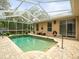 Outdoor pool area with a screened enclosure, brick pavers, and landscaping at 12060 Sapphire Dr, Spring Hill, FL 34609