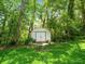 Backyard with a white shed surrounded by trees and green grass at 12060 Sapphire Dr, Spring Hill, FL 34609