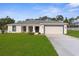 Charming single-story home featuring a well-manicured lawn, attached two-car garage, and classic architectural details at 12420 Talpa St, Spring Hill, FL 34608