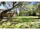 Expansive backyard with lush green lawn, mature trees providing ample shade, and a charming deck at 13901 Vacation Ln, Odessa, FL 33556