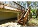 Spacious backyard featuring an outdoor deck, stairs, and ground-level parking, surrounded by lush greenery at 13901 Vacation Ln, Odessa, FL 33556