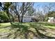Large backyard featuring a home with a deck, nestled among mature trees and a well-maintained lawn at 13901 Vacation Ln, Odessa, FL 33556