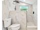 Bright bathroom featuring marble tile walls and a walk-in shower at 13901 Vacation Ln, Odessa, FL 33556