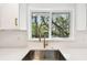 Close-up of the kitchen sink with white quartz countertops, a gold faucet, and a view of the backyard at 13901 Vacation Ln, Odessa, FL 33556