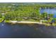 Beautiful aerial view of a lakefront park with a sandy beach, mature trees, and ample space for recreation at 13901 Vacation Ln, Odessa, FL 33556