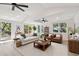 Spacious living room is staged with a white sofa, brown leather chairs and bathed in natural light from the large windows at 13901 Vacation Ln, Odessa, FL 33556
