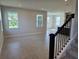 Bright open-concept living room featuring tile floors and large windows, with stairs in view at 14425 Maiden Ter, Lakewood Ranch, FL 34211
