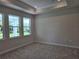 Spacious bedroom featuring tray ceiling, neutral carpet, and windows providing natural light at 14437 Maiden Ter, Lakewood Ranch, FL 34211