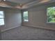 Spacious bedroom featuring plush carpeting, tray ceiling, and plenty of natural light from multiple windows at 14441 Maiden Ter, Lakewood Ranch, FL 34211