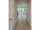 Hallway view featuring tile flooring, a white door, and three windows that let in natural light at 14441 Maiden Ter, Lakewood Ranch, FL 34211