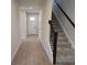 Hallway view featuring tile flooring, a white front door, and carpeted stairs with a black railing at 14441 Maiden Ter, Lakewood Ranch, FL 34211