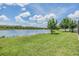 Lush backyard featuring a green lawn, a tranquil lake, and mature trees at 1783 Oak Hammock Ct, Lutz, FL 33558