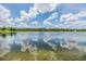 Picturesque view of a calm lake with a fountain, reflecting the clear blue sky and clouds at 1783 Oak Hammock Ct, Lutz, FL 33558