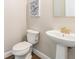 Elegant powder room showcasing a pedestal sink with gold faucet and a modern toilet at 1783 Oak Hammock Ct, Lutz, FL 33558