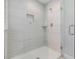 Bright and modern glass-enclosed shower featuring white subway tile and a built-in niche for added convenience at 1783 Oak Hammock Ct, Lutz, FL 33558