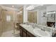 Elegant bathroom featuring dual sinks, granite counters, decorative lighting, and glass-enclosed shower at 18530 Dobson Dr, Hudson, FL 34667