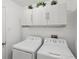 Efficient laundry room featuring upper cabinets providing ample storage above the modern washer and dryer units at 18530 Dobson Dr, Hudson, FL 34667