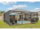 Exterior shot of a screened-in pool area with outdoor seating, grill, and lush green lawn at 18530 Dobson Dr, Hudson, FL 34667