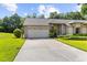 Lovely home showcasing a spacious driveway leading to a two-car garage, complemented by lush landscaping at 18736 Bent Pine Dr, Hudson, FL 34667