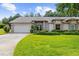 Charming home featuring a manicured lawn, complemented by lush landscaping and a two car garage at 18736 Bent Pine Dr, Hudson, FL 34667