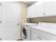Functional laundry area with white cabinets and modern washer and dryer units at 18736 Bent Pine Dr, Hudson, FL 34667