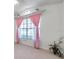 Bright bedroom featuring a large window with pink drapes and neutral tile flooring at 2048 Ground Squirrel Dr, New Port Richey, FL 34655