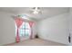 Bedroom with tile floors, fan, window with pink drapes, and vaulted ceiling shelf at 2048 Ground Squirrel Dr, New Port Richey, FL 34655