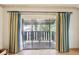 This is a covered balcony with sliding glass doors and a yellow and blue curtain at 2101 Sunset Point Rd # 201, Clearwater, FL 33765