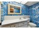Bathroom with blue patterned wallpaper, a white vanity, and a framed mirror at 2101 Sunset Point Rd # 201, Clearwater, FL 33765