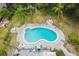 Aerial view of a community pool with surrounding palm trees, lounge chairs, and shaded tables at 2101 Sunset Point Rd # 201, Clearwater, FL 33765