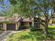 Charming home with well-manicured front yard featuring mature trees, stone accents, and lush green lawn at 2101 Sunset Point Rd # 201, Clearwater, FL 33765