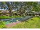 Lush green lawn with a shuffleboard court surrounded by mature trees and community buildings at 2101 Sunset Point Rd # 201, Clearwater, FL 33765