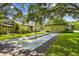 Outdoor shuffleboard court next to residential buildings with mature trees and grassy areas at 2101 Sunset Point Rd # 201, Clearwater, FL 33765