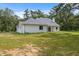 Spacious backyard featuring a bright white home, green lawn, and mature trees at 2288 Rackley Rd, Brooksville, FL 34604