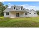 Rear of the house featuring a covered patio, bright white exterior, and lush green lawn at 2288 Rackley Rd, Brooksville, FL 34604