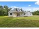 Rear of the house featuring a covered patio, bright white exterior, and lush green lawn at 2288 Rackley Rd, Brooksville, FL 34604