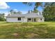 Rear of the house featuring a covered patio, bright white exterior, and lush green lawn at 2288 Rackley Rd, Brooksville, FL 34604