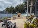 Spacious backyard features a stone outdoor fireplace, lush landscaping, comfortable seating, and a white privacy fence at 2326 Mountain Ash Way, New Port Richey, FL 34655
